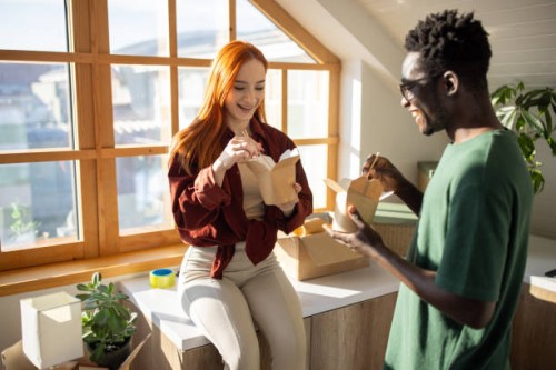 young couple eating take out noodles in their new apartment - junk food stock pictures, royalty-free photos & images