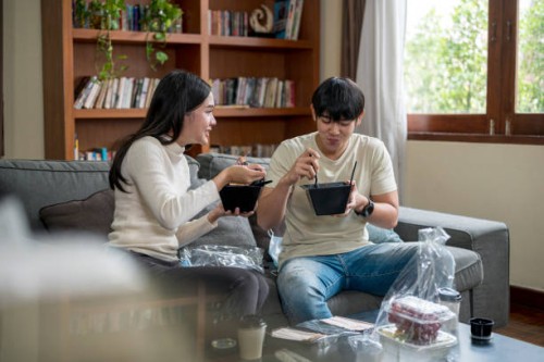 young couple enjoy eating takeout food together at home. - junk food stock pictures, royalty-free photos & images