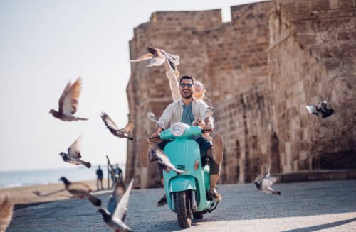 young couple having fun riding scooter in old european town - travel stock pictures, royalty-free photos & images