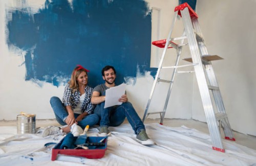young couple looking very happy painting their house - home decoration stock pictures, royalty-free photos & images