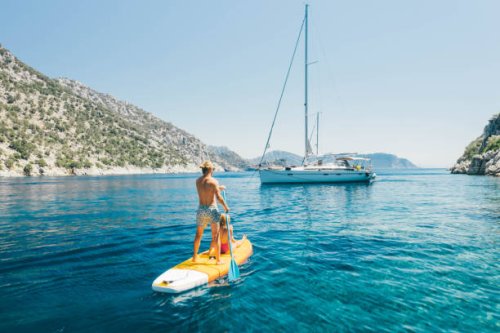 young couple paddling on stand up paddleboards against the yacht in the sea. - travel photos et images de collection