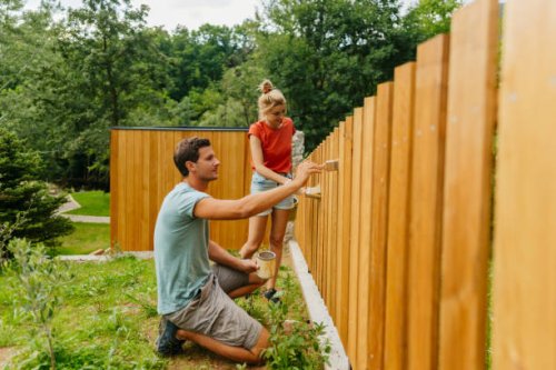 young couple painting a picket fence - home decoration stock pictures, royalty-free photos & images
