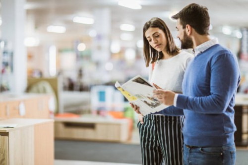 young couple reading catalog in furniture store. - home decoration stock pictures, royalty-free photos & images