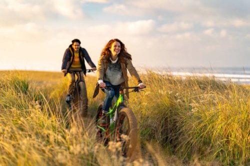 young couple ride fat bikes on coastal trail - travel stock pictures, royalty-free photos & images