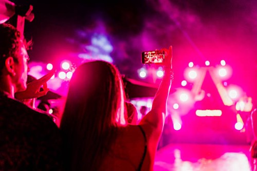 young couple taking a selfie during party outdoors - concert stockfoto's en -beelden