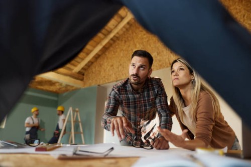 young couple talking about plans with an architect at construction site. - home decoration stock pictures, royalty-free photos & images