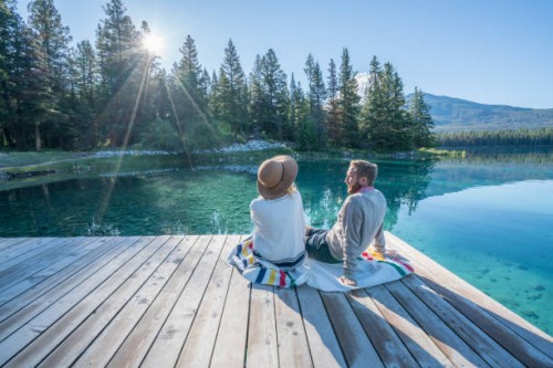 young couple watching sunrise on lake pier - travel stock pictures, royalty-free photos & images