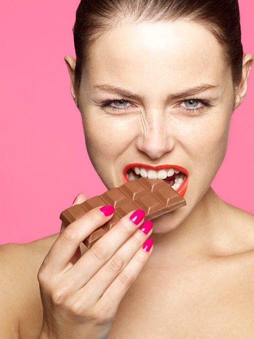 young female eating chocolate - junk food stock pictures, royalty-free photos & images