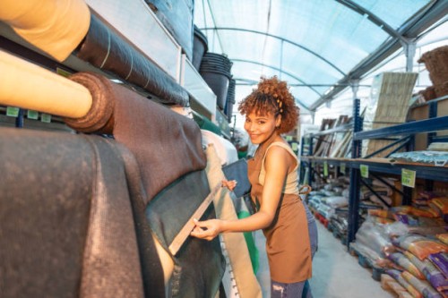 young female worker measuring and looking at blackout tarpaulins for fences, concealment fabric for home perimeter - garden decoration stock pictures, royalty-free photos & images