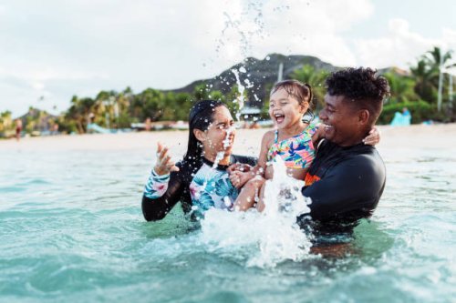 young girl and adult friends splash in the ocean together - travel stock pictures, royalty-free photos & images