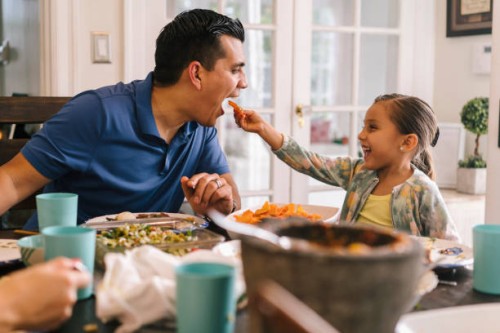 young girl feeding her father at dinner table - food stock pictures, royalty-free photos & images