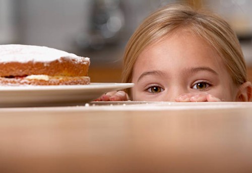 young girl in kitchen peeking over counter with a cake on it - junk food stock pictures, royalty-free photos & images