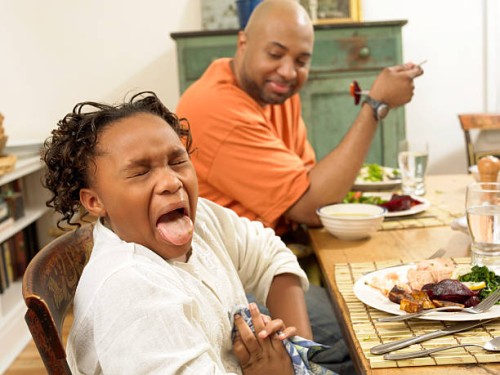 young girl sits at a table for lunch with her father, sticking out her tongue in disgust at the food - food stock pictures, royalty-free photos & images
