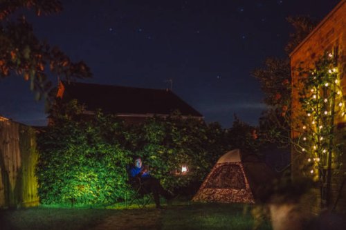 young handsome man reading with his ebook reader next to a camping tent in the backyard of house - garden decoration stock pictures, royalty-free photos & images