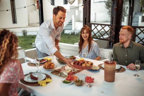 young handsome man serving food for his friends in his backyard - garden decoration photos et images de collection
