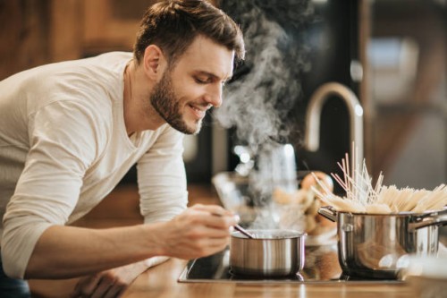 young happy bachelor enjoying in the smell of his cooking. - food stock pictures, royalty-free photos & images