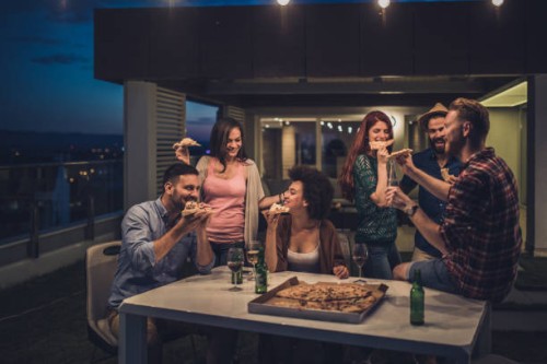 young happy people having a dinner party during the night on a terrace. - junk food stock pictures, royalty-free photos & images