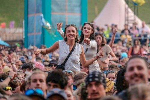 Young lady on the shoulders of a friends in crowd enjoys live music at Boomtown Fair Festival. Boomtown aka Boomtown Fair is a British music festival...