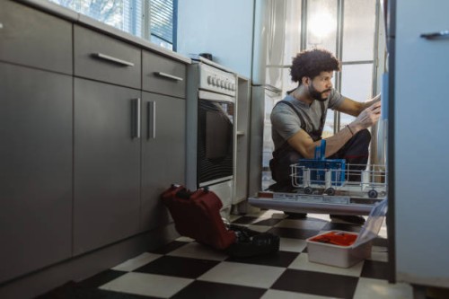 young latin handyman repairs the dishwasher in the client's kitchen - home decoration stock pictures, royalty-free photos & images