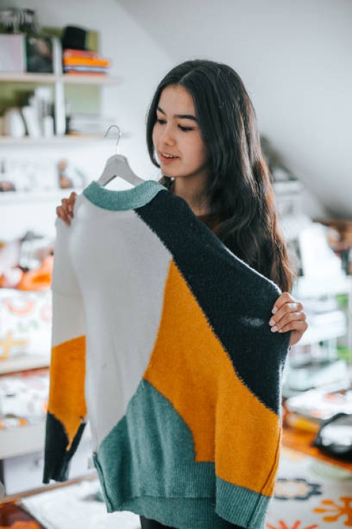young latina woman choosing a sweater from her closet - fashion photos et images de collection