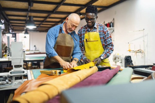 young man black ethnicity, learning craft from an senior tailor, at the leather workshop - fashion stock pictures, royalty-free photos & images