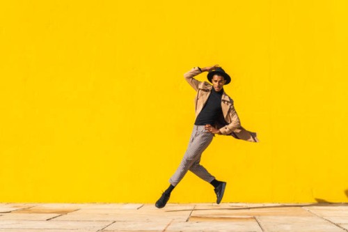 young man dancing in front of yellow wall, jumping mid air - fashion stock pictures, royalty-free photos & images