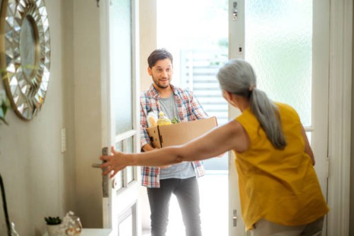 young man delivering groceries to elderly woman at home - food stock pictures, royalty-free photos & images