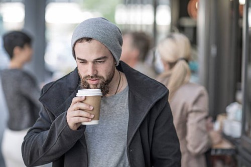young man drinking takeaway coffee in the city - junk food stock pictures, royalty-free photos & images
