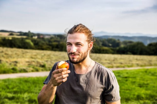 young man eating an apple in rural landscape - food stock pictures, royalty-free photos & images