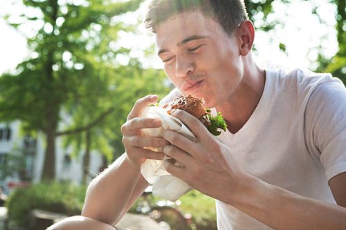 young man eating hamburger - junk food stock pictures, royalty-free photos & images