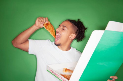 young man eating take out pizza - junk food stock-fotos und bilder