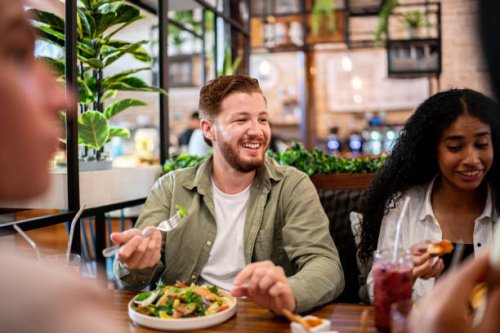young man eating with his friends on a restaurant - food stock pictures, royalty-free photos & images