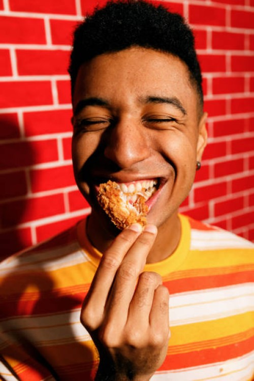 young man enjoying crispy chicken - junk food stock pictures, royalty-free photos & images