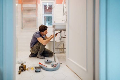 young man fixing a leak under the bathroom sink - home decoration stock pictures, royalty-free photos & images