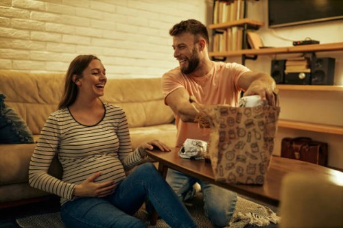 young man having dinner on the floor with his pregnant wife - junk food stock pictures, royalty-free photos & images