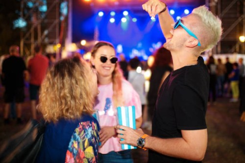 young man having fun eating popcorn on music festival, female friends laughing - concert stock pictures, royalty-free photos & images