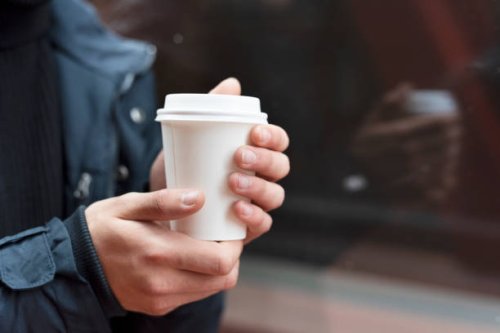 young man holding a takeaway coffee outdoors - junk food stock pictures, royalty-free photos & images