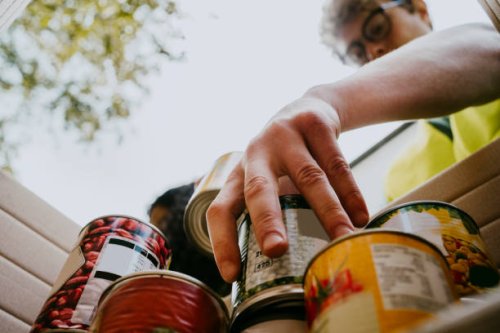 young man holding canned food in box - food stock pictures, royalty-free photos & images