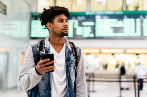 young man inside the airport holding a mobile phone. - travel photos et images de collection
