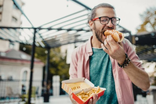 young man is eating hot dog - junk food stock pictures, royalty-free photos & images