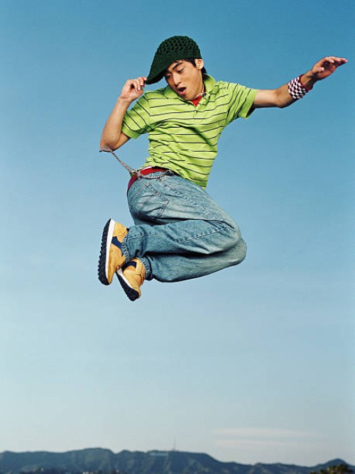 young man jumping in air, portrait, low angle - fashion stock-fotos und bilder