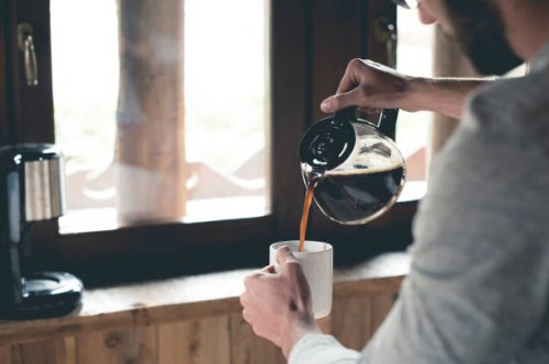 young man pouring coffee into cup at home - coffee stock pictures, royalty-free photos & images