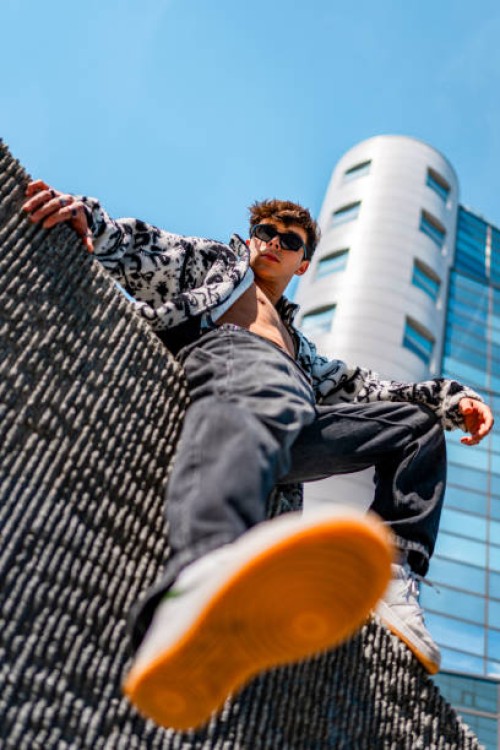 young man sitting on a concrete wall - fashion stock pictures, royalty-free photos & images