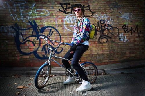 young man sitting on bike. - fashion stock-fotos und bilder