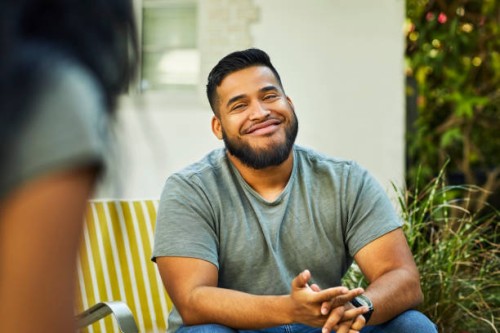 young man smiling in yard during social gathering - garden decoration photos et images de collection
