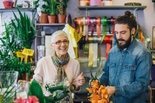 young man trimming flowers with a florist - garden decoration stock pictures, royalty-free photos & images