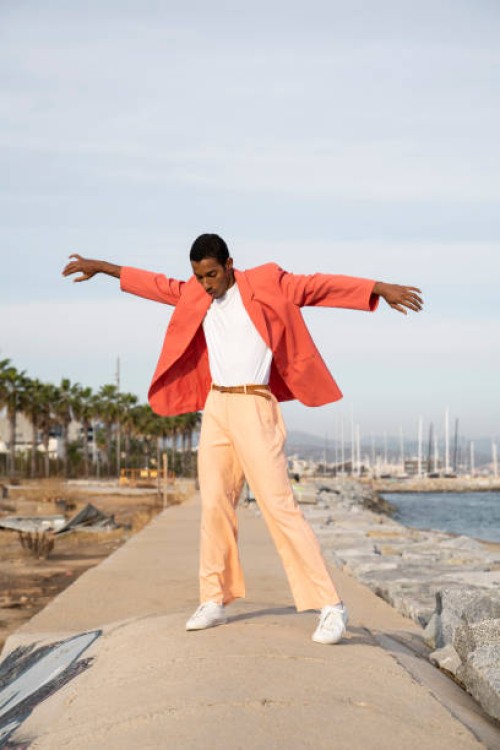 young man with arms outstretched dancing while standing against sky - fashion stock pictures, royalty-free photos & images