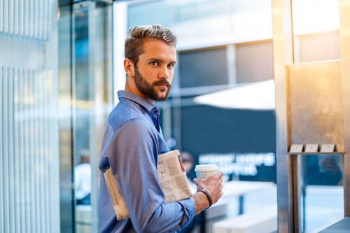 young man with newspaper and takeaway coffee - junk food stock pictures, royalty-free photos & images