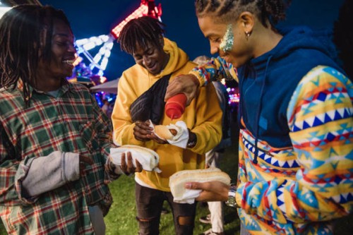 young men eating festival hot dogs - junk food stock pictures, royalty-free photos & images