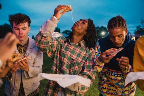 young men eating pizza at festival - junk food stock pictures, royalty-free photos & images